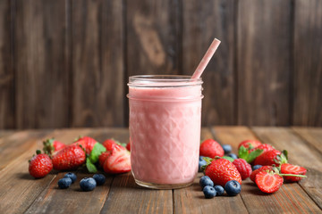 Glass jar with milkshake on wooden table