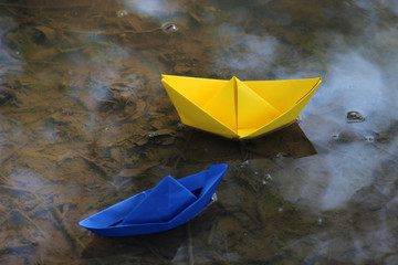 tow paperboats in a puddle