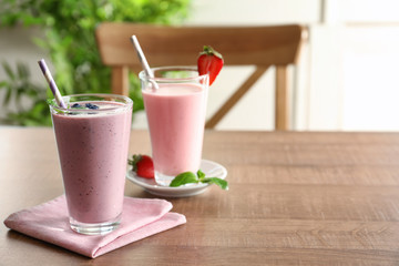 Glasses with different milkshakes on wooden table