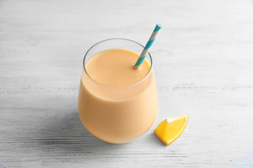 Glass with orange milkshake on table