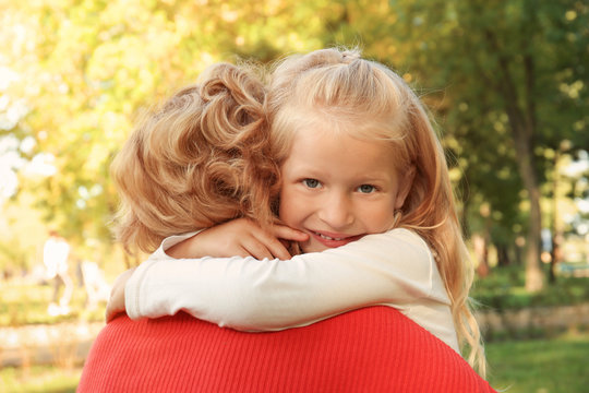 Cute little girl hugging grandmother in park