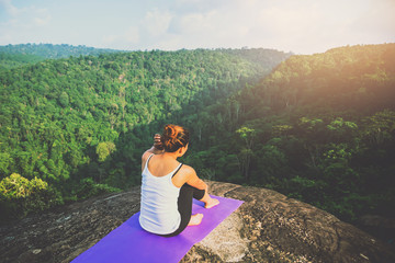 Naklejka premium Asian women relax in the holiday. Play if yoga. On the Moutain rock cliff. Nature of mountain forests in Thailand
