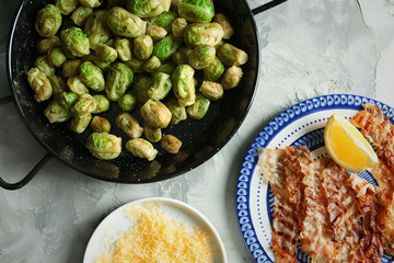 Composition with Brussels sprouts, bacon and grated cheese on table