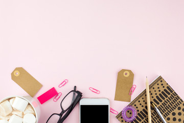 Creative flat lay photo of workspace desk with smartphone, eyeglasses, pen, pencil and notebook with copy space background, minimal style on pink background
