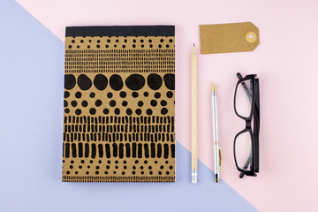 Creative flat lay photo of workspace desk with smartphone, eyeglasses, pen, pencil and notebook, minimal style on pink background. Minimal business concept