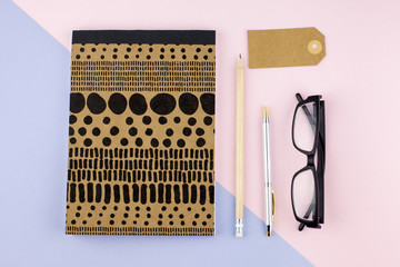 Creative flat lay photo of workspace desk with smartphone, eyeglasses, pen, pencil and notebook, minimal style on pink background. Minimal business concept