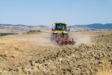 Obraz premium Peasant on the tractor while preparing the field for sowing
