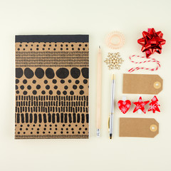 Creative flat lay photo of workspace desk with eyeglasses, pen, pencil and notebook, minimal style on cream background. Minimal Chtistmas shopping concept with tags and christmas decoration