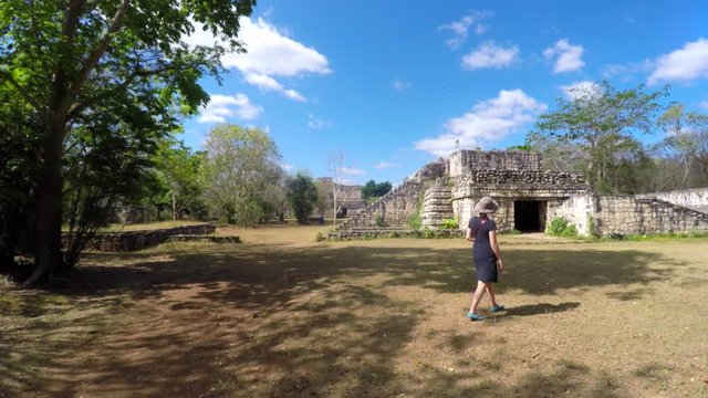 A gimbal shot of woman walking through mayan ruins at ek balam