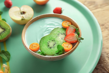 Bowl with yummy spirulina smoothie on tray. Healthy vegan food concept