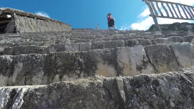 A gimbal shot of woman walking up mayan ruins at ek balam
