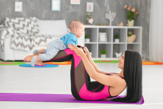 Young mother doing exercises while holding baby at home