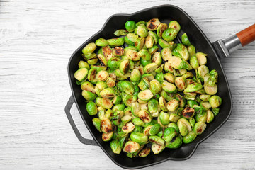 Grill pan with roasted brussel sprouts on wooden background