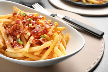 Plate with french fries and bacon on table