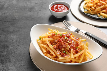 Plate with french fries and bacon on table