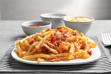 Plate with french fries and bacon on table