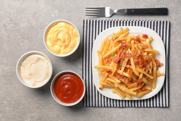 Plate with french fries and bacon on table