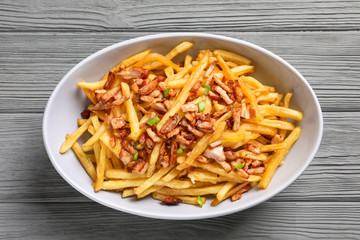 Plate with french fries and bacon on wooden background