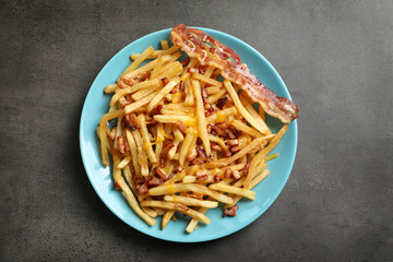 Plate with french fries and bacon on grey background