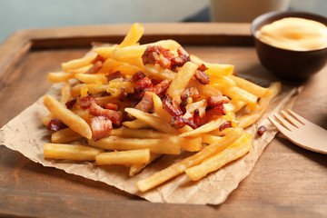 Wooden board with french fries and bacon, closeup