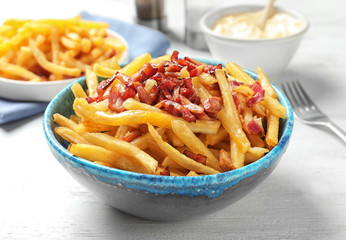 Bowl with french fries and bacon on table