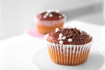Tasty muffin with caramel and chocolate toppings on blurred background