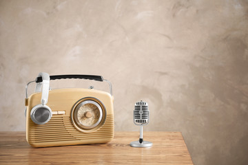 Retro radio, headphones and microphone on table against light wall - obrazy, fototapety, plakaty