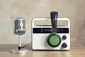 Retro radio, headphones and microphone on table against light wall