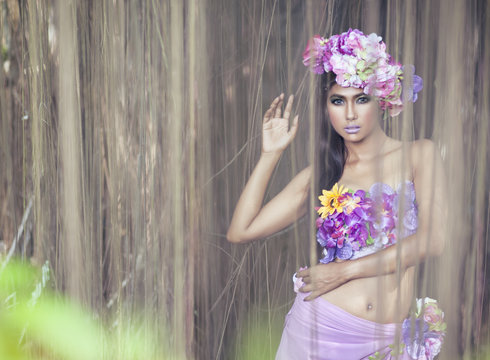 Young Asian Woman Tanned Skin And Black Shine Long Hair with flowers costume design. Fancy fairy nymp in the jungle.