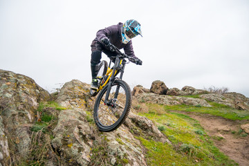 Professional Cyclist Riding Mountain Bike Down the Rocky Hill. Extreme Sport and Enduro Biking Concept.