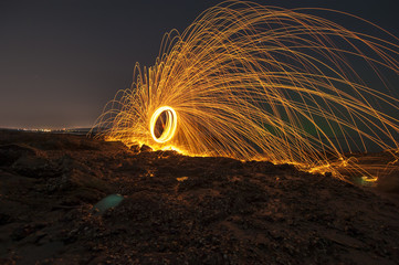 Showers of hot glowing sparks from spinning steel wool on the beach