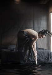 Asian ballerina woman in black swan top nude concept costume wearing pink ballet shoes in the dark bed room natural window light with digital reflection effect.