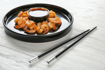Plate with fresh tasty shrimp basket and sauce on table