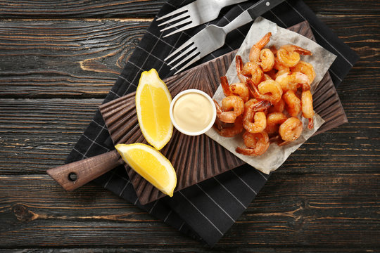 Board with fresh tasty shrimp basket and sauce on table