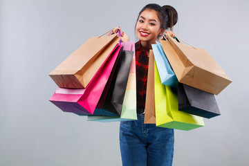 Happy asian woman at shopping holding many bags. Isolated on gray background on black friday holiday. Copy space for sale ads.