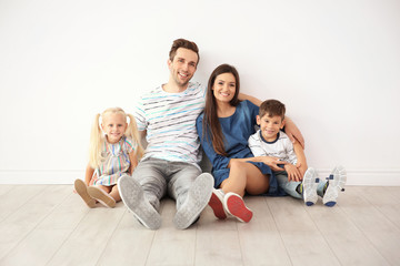 Happy family sitting near wall in their new home