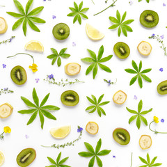 Composition of fruits and flowers. Fruit pattern. Plants and fruits on a white background. Slices of kiwi and bananas with green leaves and flowers. Top view, flat lay. Floral abstract background.