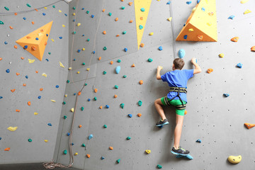 Young boy climbing wall in gym