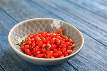 Bowl with fresh goji berries on wooden table
