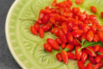 Plate with fresh goji berries on table, closeup