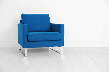 Comfortable blue armchair on white wall background