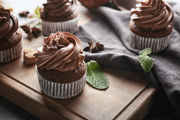 Tasty chocolate cupcakes on wooden board