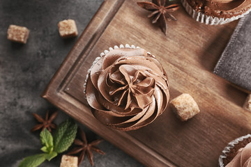 Tasty chocolate cupcake on wooden board