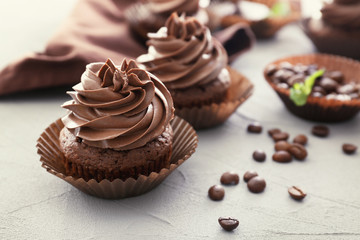Tasty chocolate cupcake on textured background