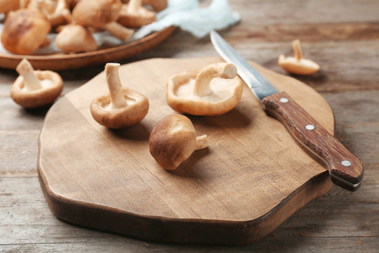 Board with raw shiitake mushrooms on wooden table
