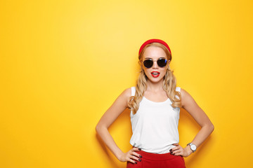 Attractive hipster girl with sunglasses on color background