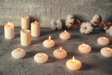 Many burning candles on table