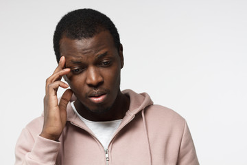 Upset unhappy young african american man touching head with hand, suffering from headache. People,...