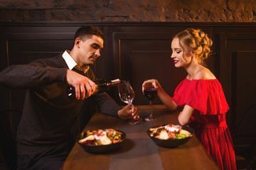 Man pours wine into a glass, couple in restaurant