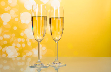 Two glasses of champagne with bubbles on bright yellow